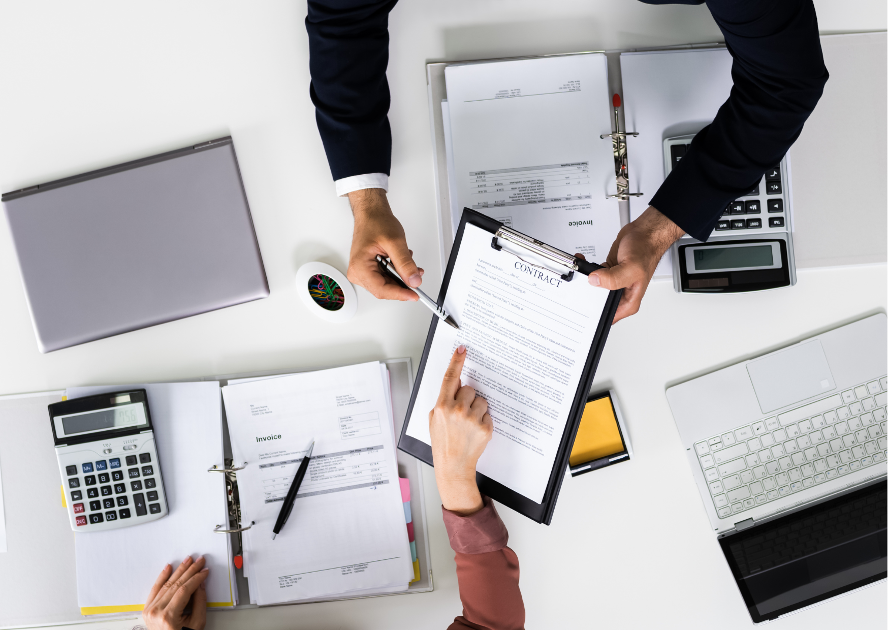 An image of a desk with a contract being signed