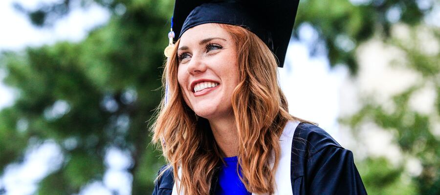 A young woman in graduation cap and gown smiling on her graduation day