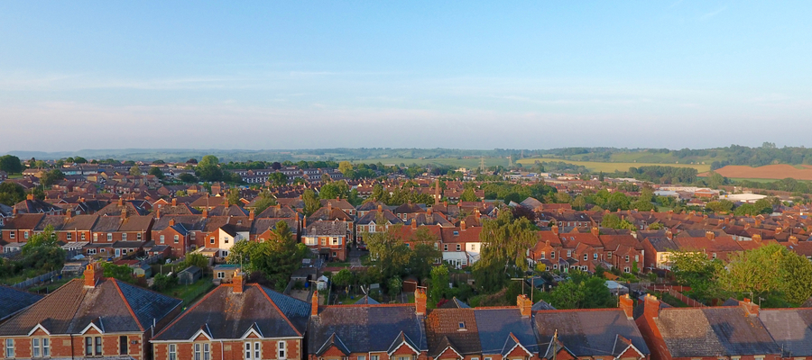 An aerial photo of brick houses in the UK with blue skies and country side