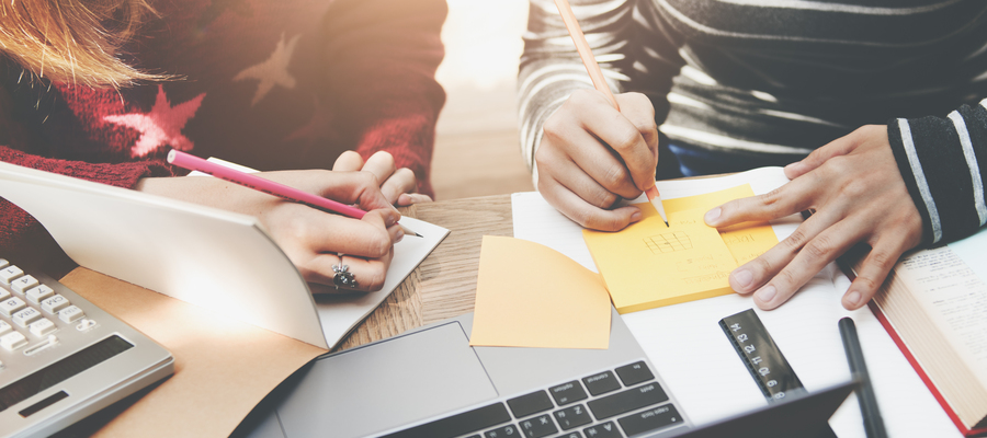 Two people writing on post it notes