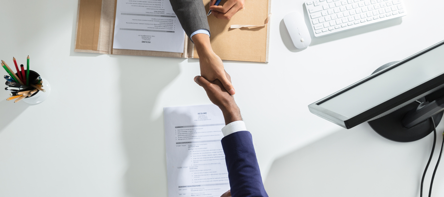 Two people handshaking upon a desk