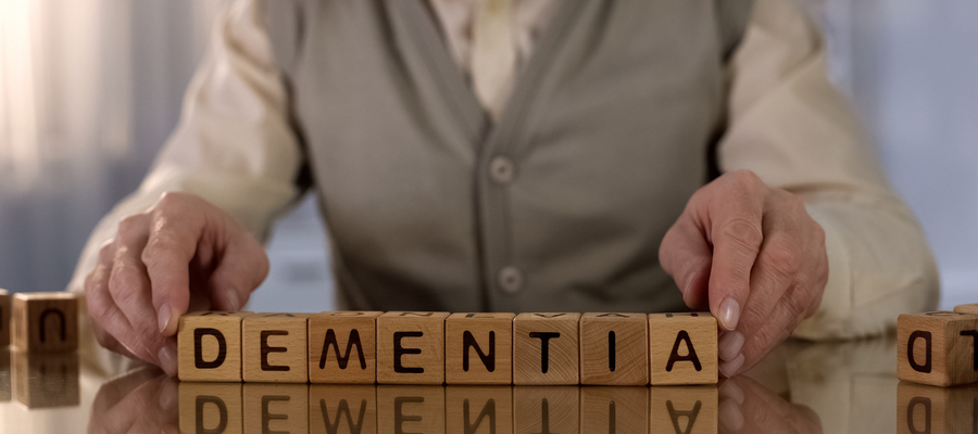 An elderly man holding wooden blocks that spell Dementia 