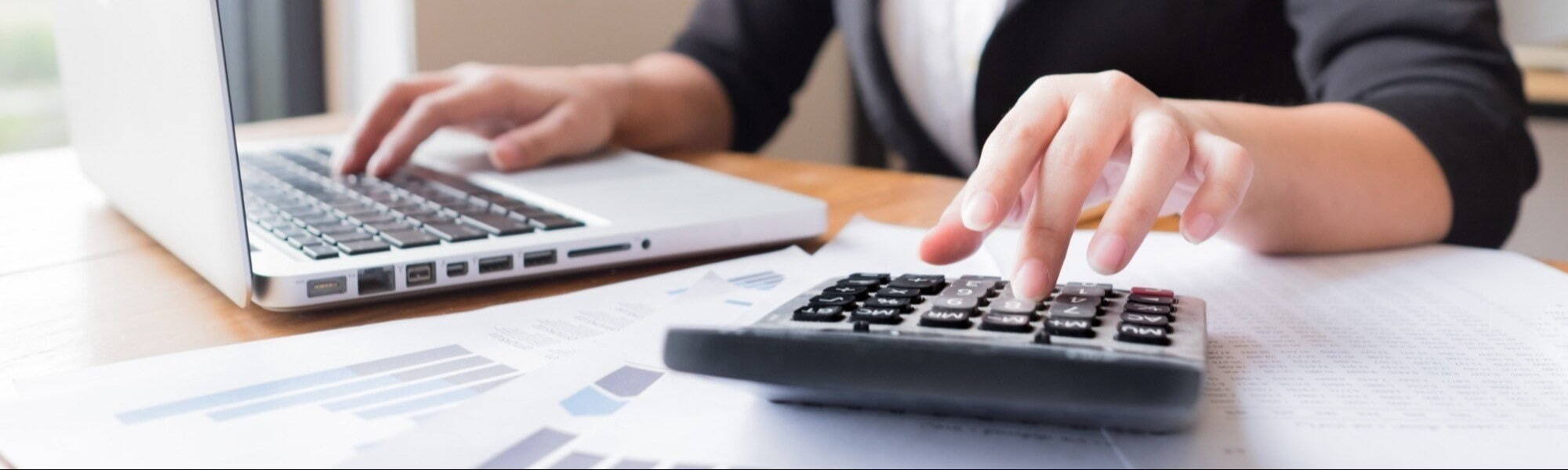 A laptop and calculator being used at the desk