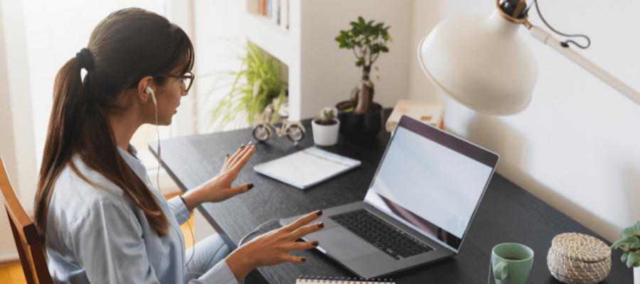 A woman with brown hair speaking on a work call from her laptop