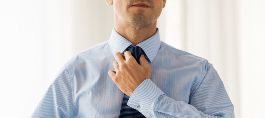 A man getting ready for an interview and putting his tie on.